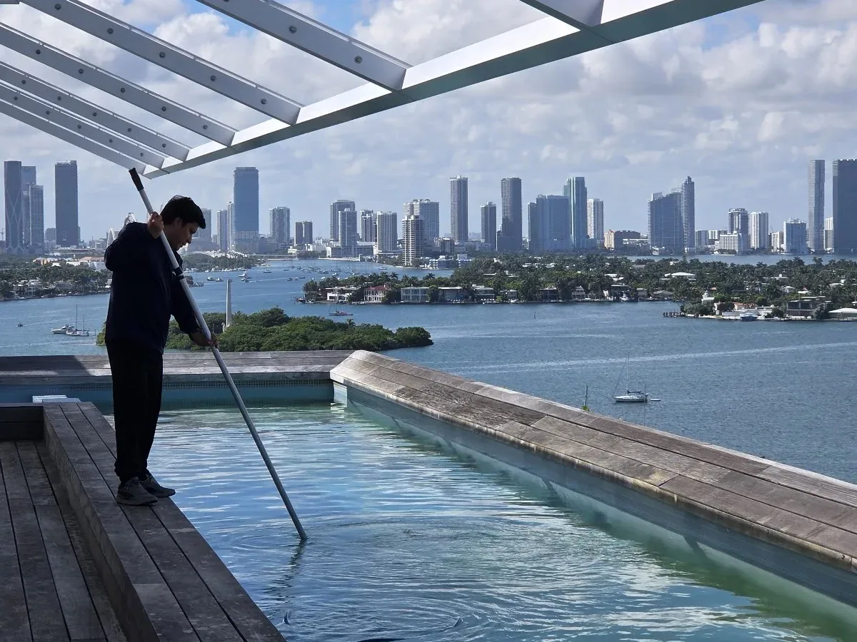 Blueviel technician servicing a rooftop pool overlooking the Miami skyline and bay