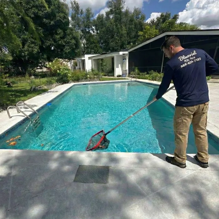 Blueviel technician in branded uniform skimming a residential pool in Miami